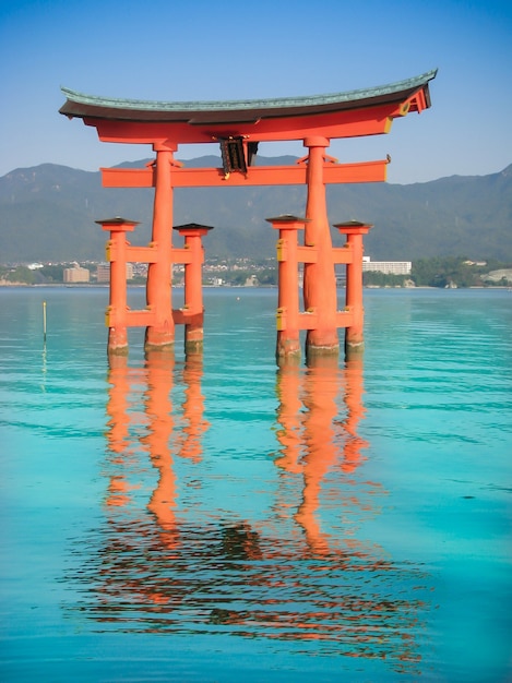 De oranje grote Japanse heiligdompoort op het water in het overzees