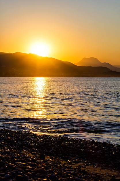 De oranje zonsopgang onder bergen en zee