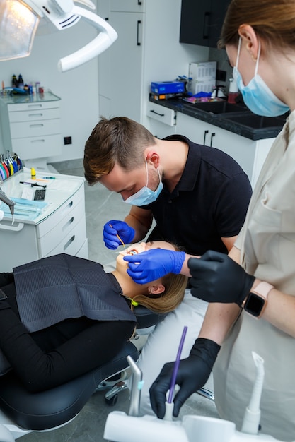 De orthodontist zet metalen beugels op de tanden van de patiënt. Orthodontische tandheelkundige behandeling. Hoge kwaliteit foto