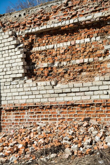 De oude baksteen van een verlaten bouwmuur beschadigd door tijd en weer