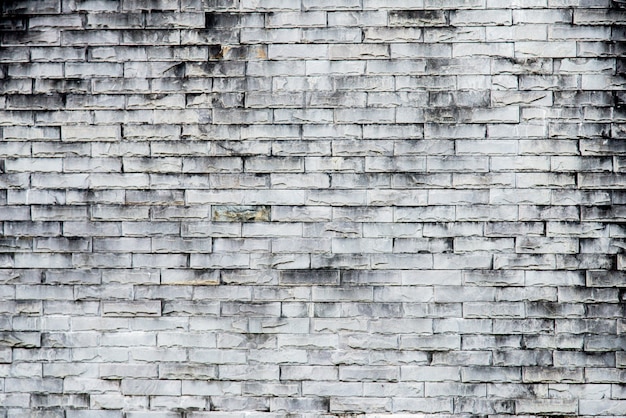 De oude grijze achtergrond van de bakstenen muurtextuur. ruwe bakstenen muur. achtergrond van oude uitstekende vuile bakstenen muur met schilpleister, textuur
