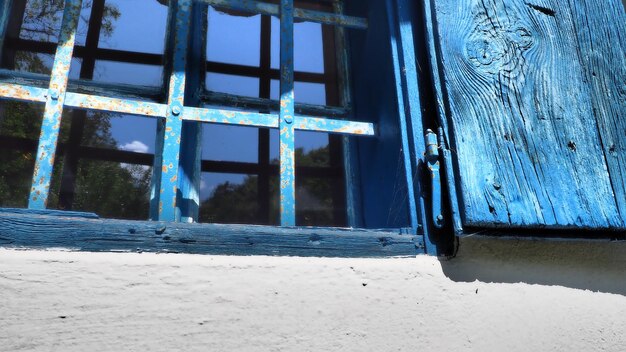 De oude houten luiken zijn open De houten kozijnen en luiken zijn blauw geverfd Witte betonnen muur Traditionele rustieke architectuur Glazen raam Trsic Loznica Servië