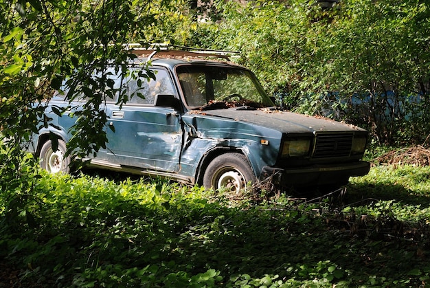 De oude kapotte LADA-auto leeft zijn leven in de bosjes