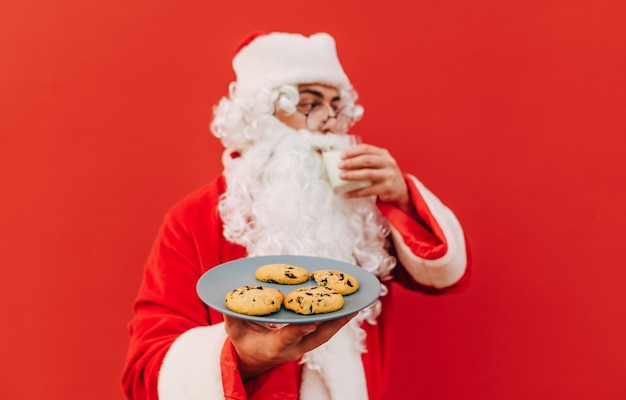 De oude Kerstman houdt een bord met lekkere koekjes vast