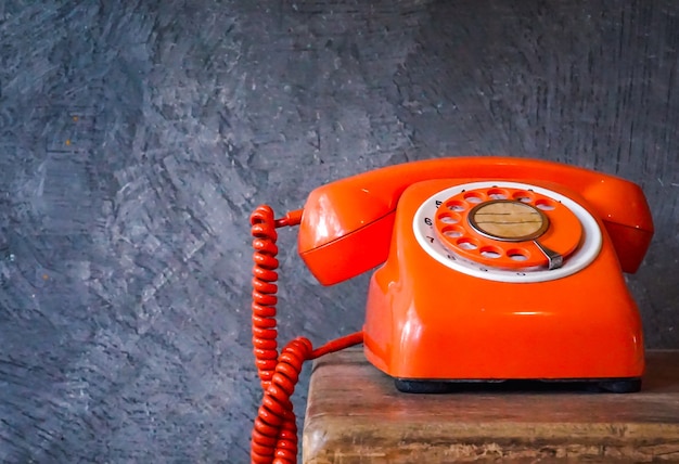 De oude oranje telefoon rinkelt met handset uit Retro roterende telefoon op houten tafel