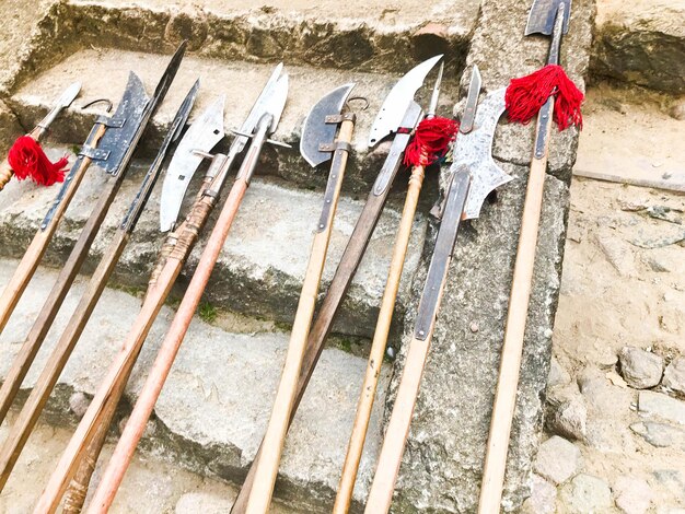 De oude oude middeleeuwse koude wapens assen hellebaarden messen zwaarden met houten handvatten likken op de stenen trappen van het kasteel