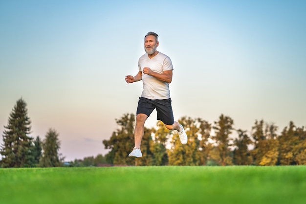 De oude sportman die op het gras rent