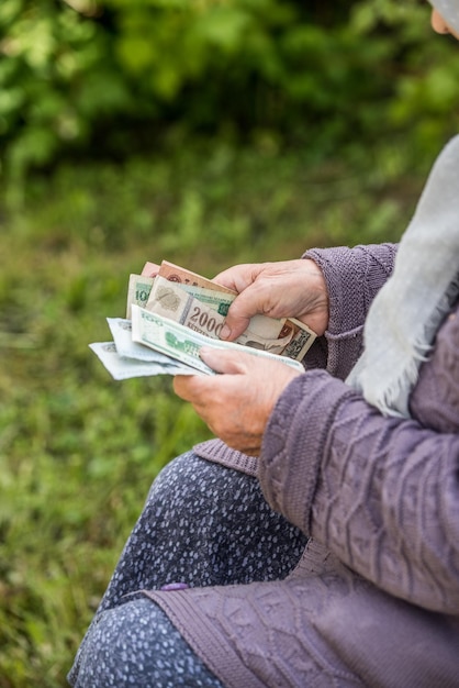 De oude vrouw beschouwt bankbiljetten handen en geld close-up