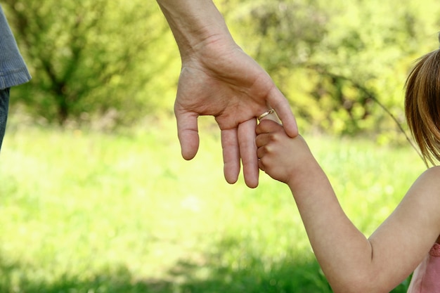 De ouder die de hand van het kind vasthoudt