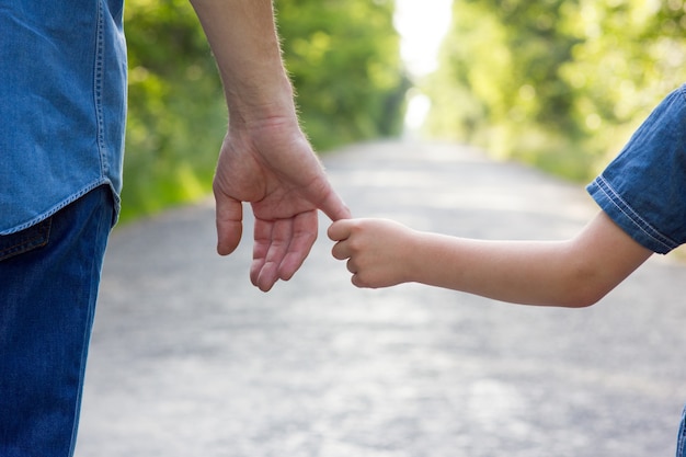 De ouder houdt de hand van een klein kind vast op een wegconceptfamilie