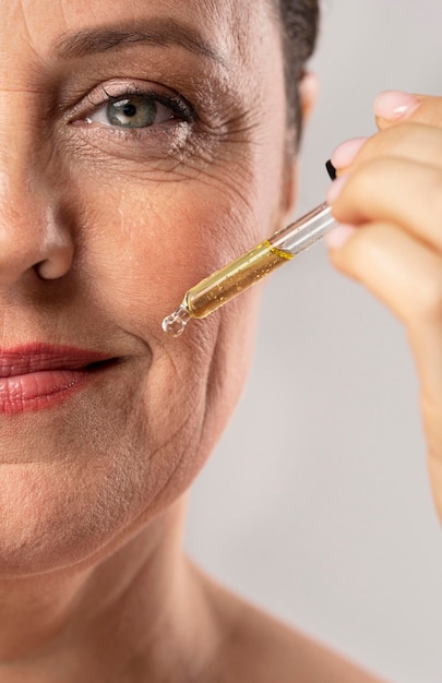 Foto de oudere vrouw die van smiley serum gebruikt voor haar mondrimpels