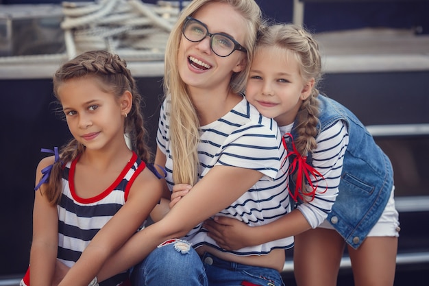 De oudere zus en jongere zusjes en een broer in maritieme stijl tegen de achtergrond van boten en jachten