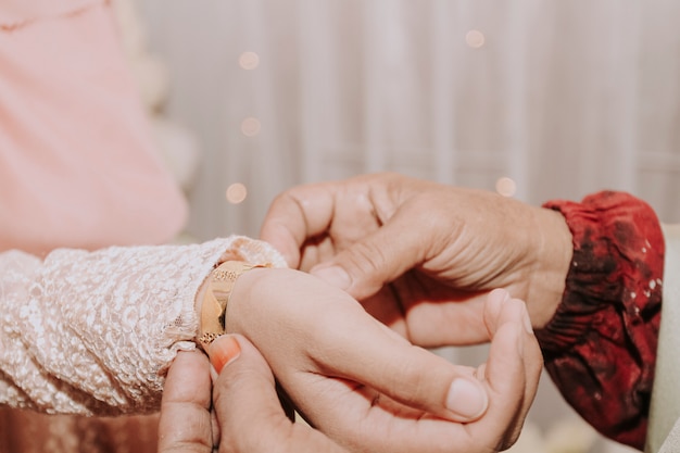 De ouders van de bruidegom hingen een armband om de arm van de bruid