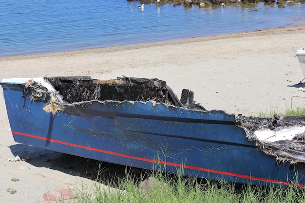 De overblijfselen van een boot die in brand vloog, strandde op een strand