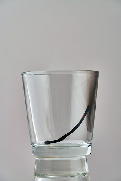 De overblijfselen van een verbrande lucifer liggen in een transparant glas
