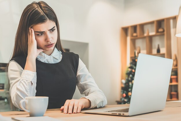 De overstuur vrouw met een laptop aan tafel