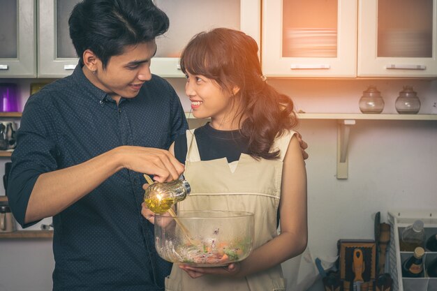 Foto de paarman en de vrouw glimlachen gelukkig en voorbereiden een salade voor ontbijt