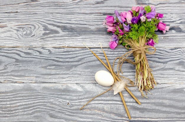 De paascompositie Eieren een boeket van anemonen en kaarsen op houten tafel close-up