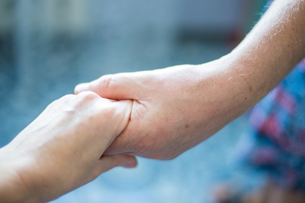 De palm van een vrouw is in de hand van een man. Huiselijk geweld