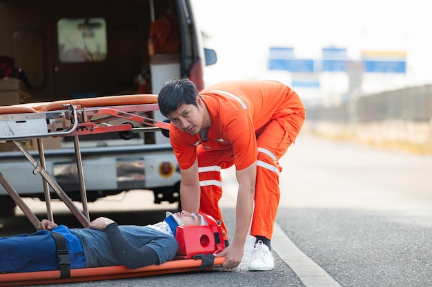 De paramedicus helpt een gewonde man in een noodsituatie op de weg