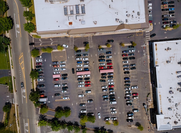 De parkeerplaats is bijna volledig gevuld met kleurrijke auto's in de buurt van het winkelcentrum vanaf de hoogte van de vogelvlucht.