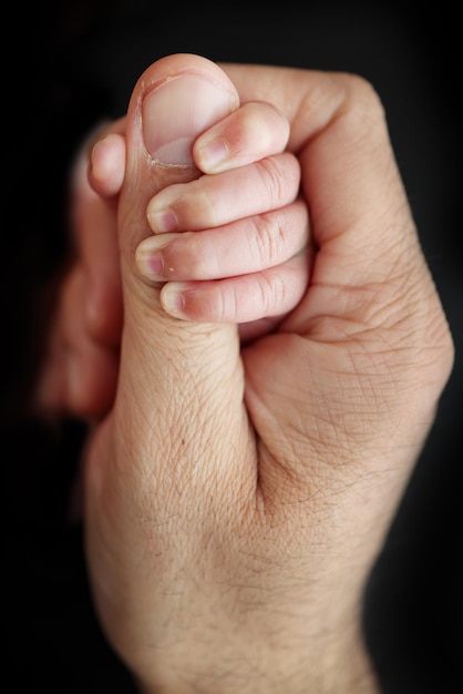 De pasgeboren baby heeft een stevige grip op de parent39s vinger na de geboorte Close-up handje van kind en palm van moeder en vader Ouderschap kinderopvang en gezondheidszorg concept Professionele macro foto