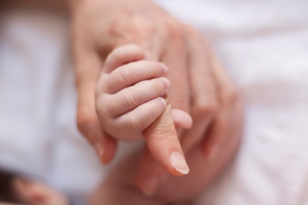 Foto de pasgeboren baby houdt de vinger van zijn moeder vast.