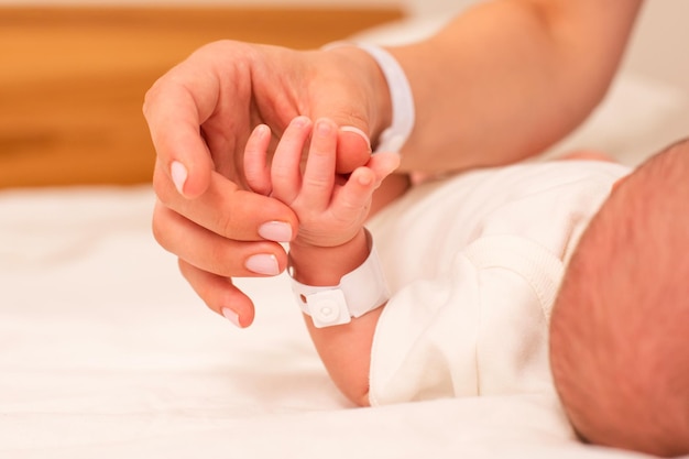 De pasgeboren baby ligt op een witte deken Naast hem is zijn moeder die zijn hand vasthoudt Focus op hun handen