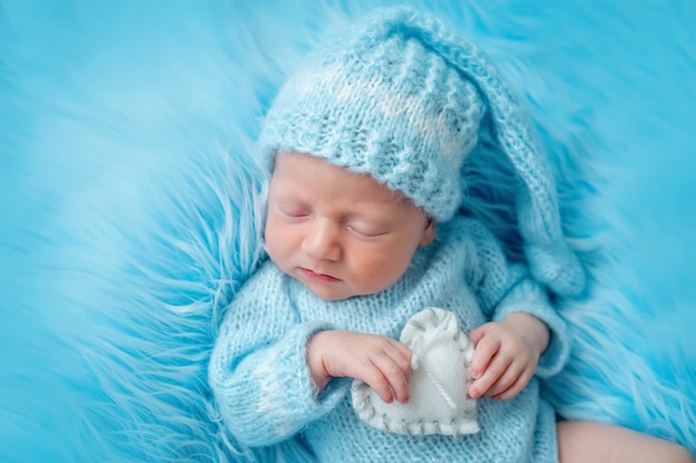 De pasgeboren slaap van de babyjongen met een stuk speelgoed, bekijkt recht, portret, 14 dagen
