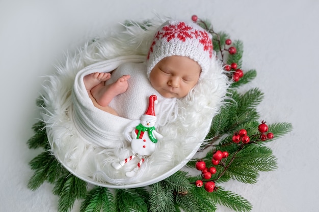 De pasgeboren slaap van het babymeisje onder Kerstboom met in hand suikergoed, gezonde babyslaap