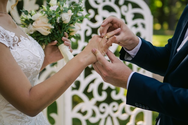 De pasgetrouwden wisselen ringen uit, in de buurt van de huwelijksboog, tijdens de huwelijksceremonie. jong bruidspaar