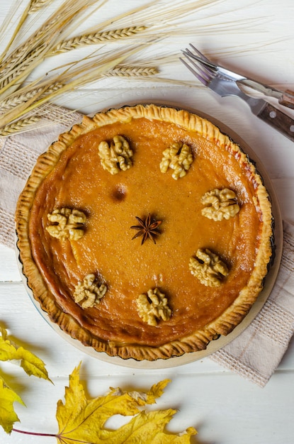 De pastei van de pompoen eigengemaakte veganist en kruidenkaneel, anis, oranje pompoenen met het decor van de yelllow droge herfstbladeren op donkere lijstachtergrond.