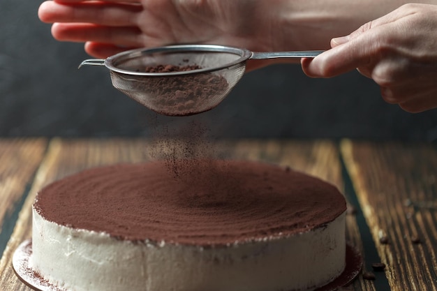 Foto de patissier versiert de taart met tiramisu cacaopoeder