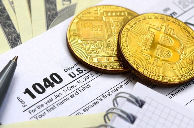 De pen, bitcoins en dollarbiljetten liggen op het belastingformulier 1040 us individual income tax return. de tijd om belasting te betalen