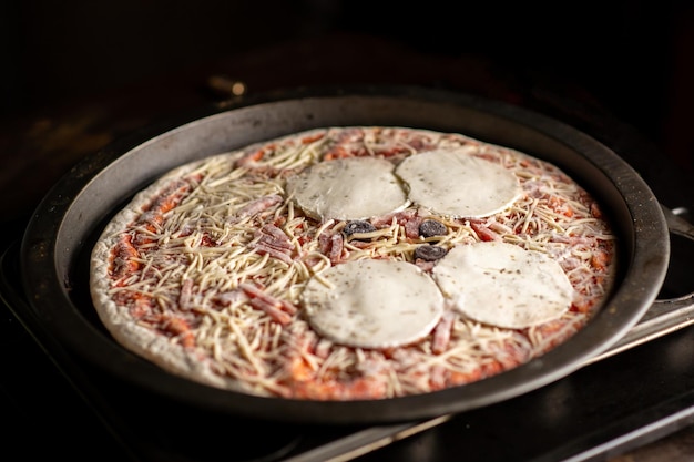 De pizza gaat de oven in Pizza met grote bollen kaas Homecooking