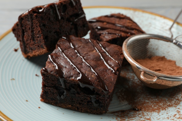 De plaat met de plakken van de chocoladecake en de zeef met poeder op houten, sluiten omhoog