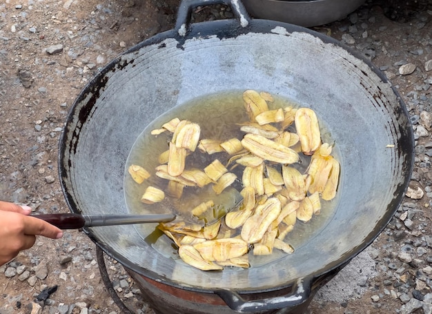 De plakjes banaan worden gebakken in hete plantaardige olie voor het maken van bananenchips