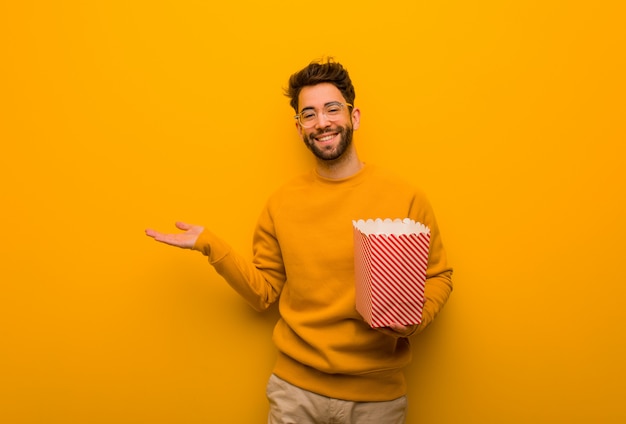 De popcorns die van de jonge mensenholding iets met hand houden