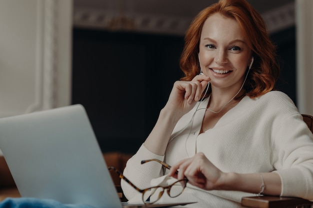 De positieve vrouw heeft videogesprek met vriend via laptop computer