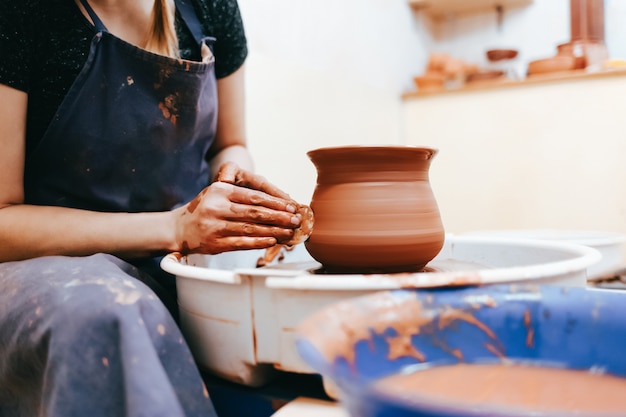 De pottenbakker van de vrouw het vormen kleischotels op een aardewerkwiel