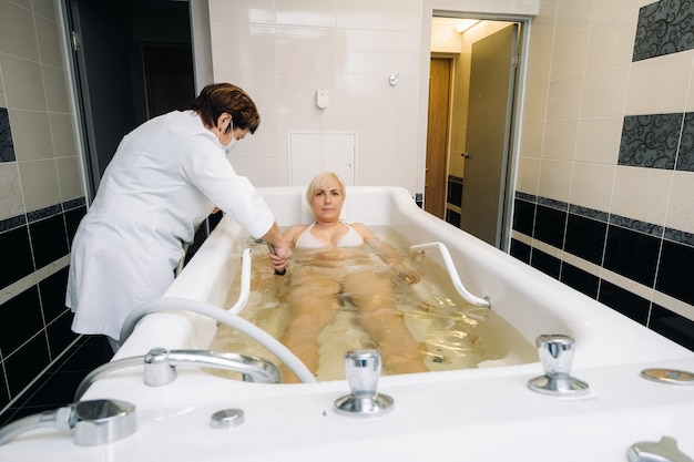 De procedure van onderwaterdouchemassage in de badkamer. Meisje over de procedure van onderwatermassage.