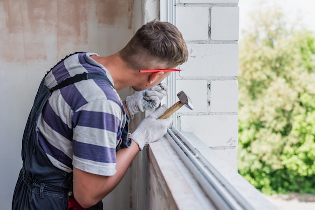 De proces mannelijke arbeider die venster in een huis herstellen, sluit omhoog