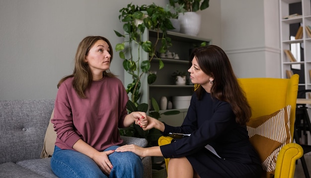 De psycholoogvrouw legde haar hand op de schouder van de overstuur vrouwelijke patiënt. Een gebaar van steun. Psychologische hulp aan een vrouw