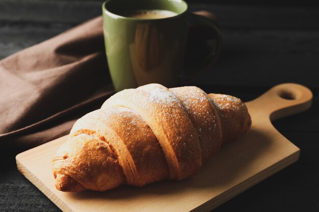 De raad met croissant en de kop van koffie op houten achtergrond, sluiten omhoog