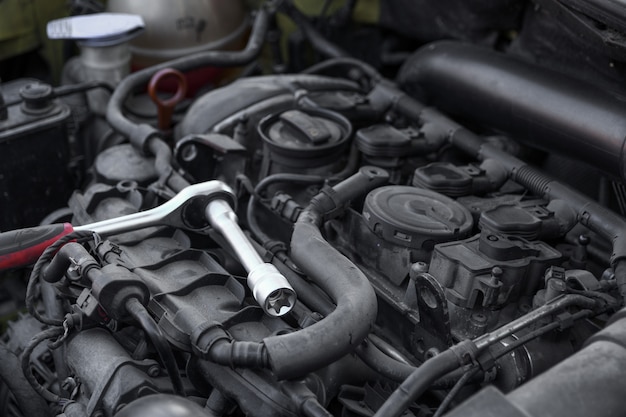 De ratelsleutel met de sproeikop rust op de automotor. Auto reparatie