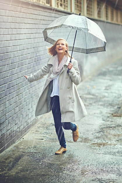 De regen stoorde haar sowieso nooit Volledig shot van een aantrekkelijke jonge vrouw die in de regen speelt