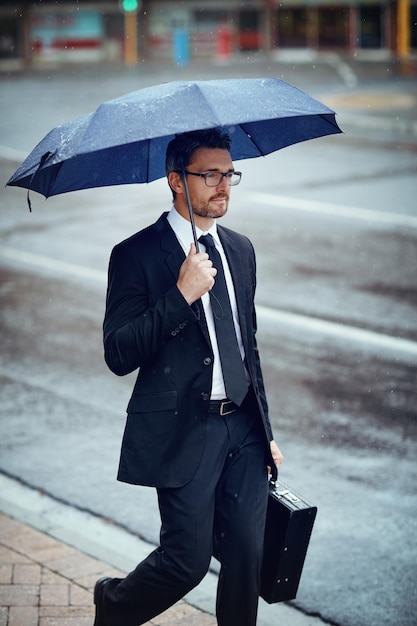 De regen zal zijn focus op slagen niet belemmeren Shot van een volwassen zakenman die een paraplu vasthoudt terwijl hij in de stad is