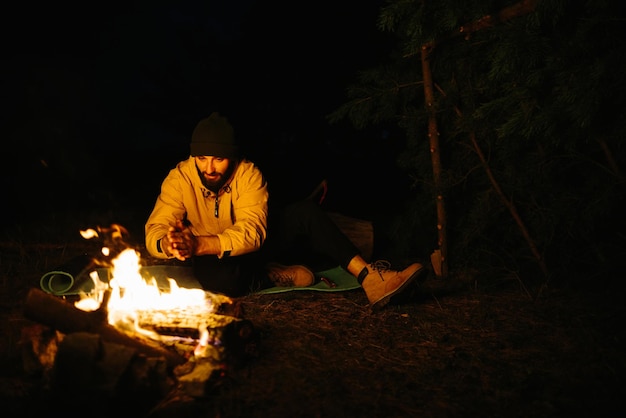 De reiziger rust bij het nachtelijke kampvuur Ingerichte beschutting tegen takken om te slapen met een petroleumlamp en een vuur omringd door stenen