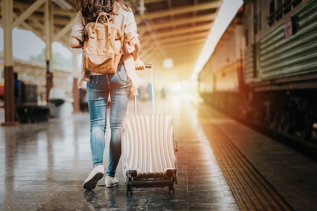 De reizigerstoerist die van de vrouw met bagage bij station loopt.