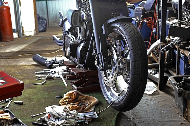 De rij van schroeven en moersleutelhulpmiddelen op een vloer in workshop herstelde dichtbij oude fiets of motorfietsmotor. industriële scène met apparatuur